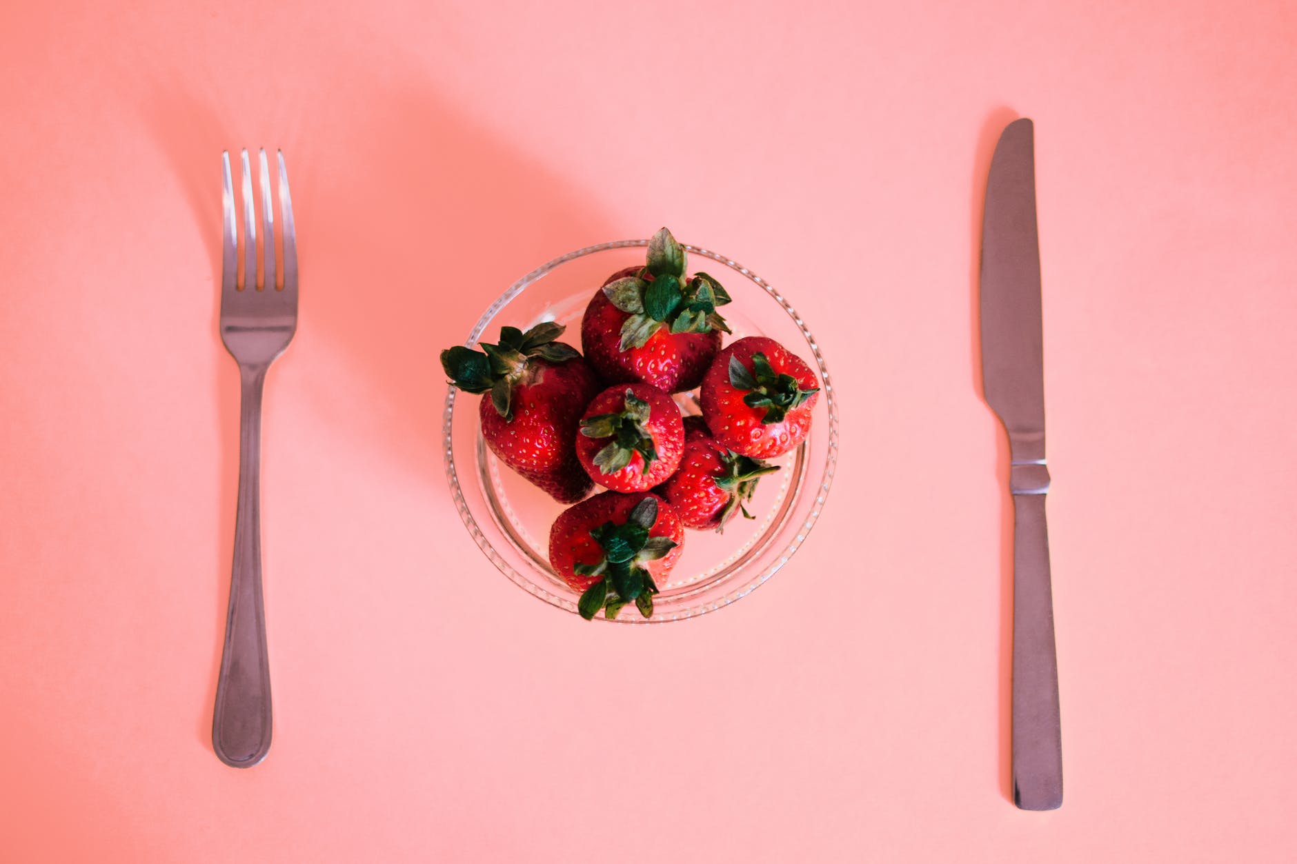 bowl of strawberry in front of dining knife and fork